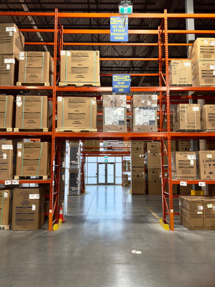 khóa cửa kho nhà xưởng – kho thành phẩm với kệ hàng chất đầy thùng carton chờ xuất hàng 2026